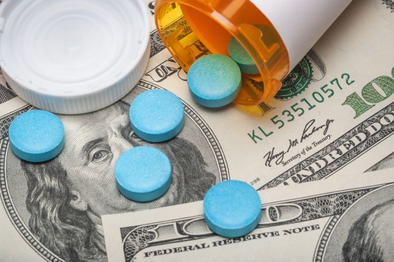 Prescription pills on top of U.S. currency, illustrating out-of-pocket Medicare costs